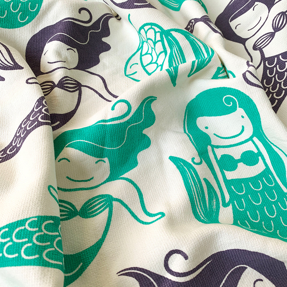 A close up of a Mapayah cotton bath towel featuring a mermaid print, neatly folded to show the design, fabric quality, and softness.