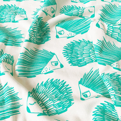 
A close up of a Mapayah cotton bath towel featuring a green porcupine print, neatly folded to show the design, fabric quality, and softness.
