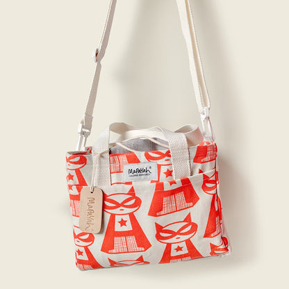 A off white canvas lunch bag with a red super cat pattern, featuring a shoulder strap, top handles, and a hanging brand tag. The brand 'Mapayah' is visible on the tag and a central label.