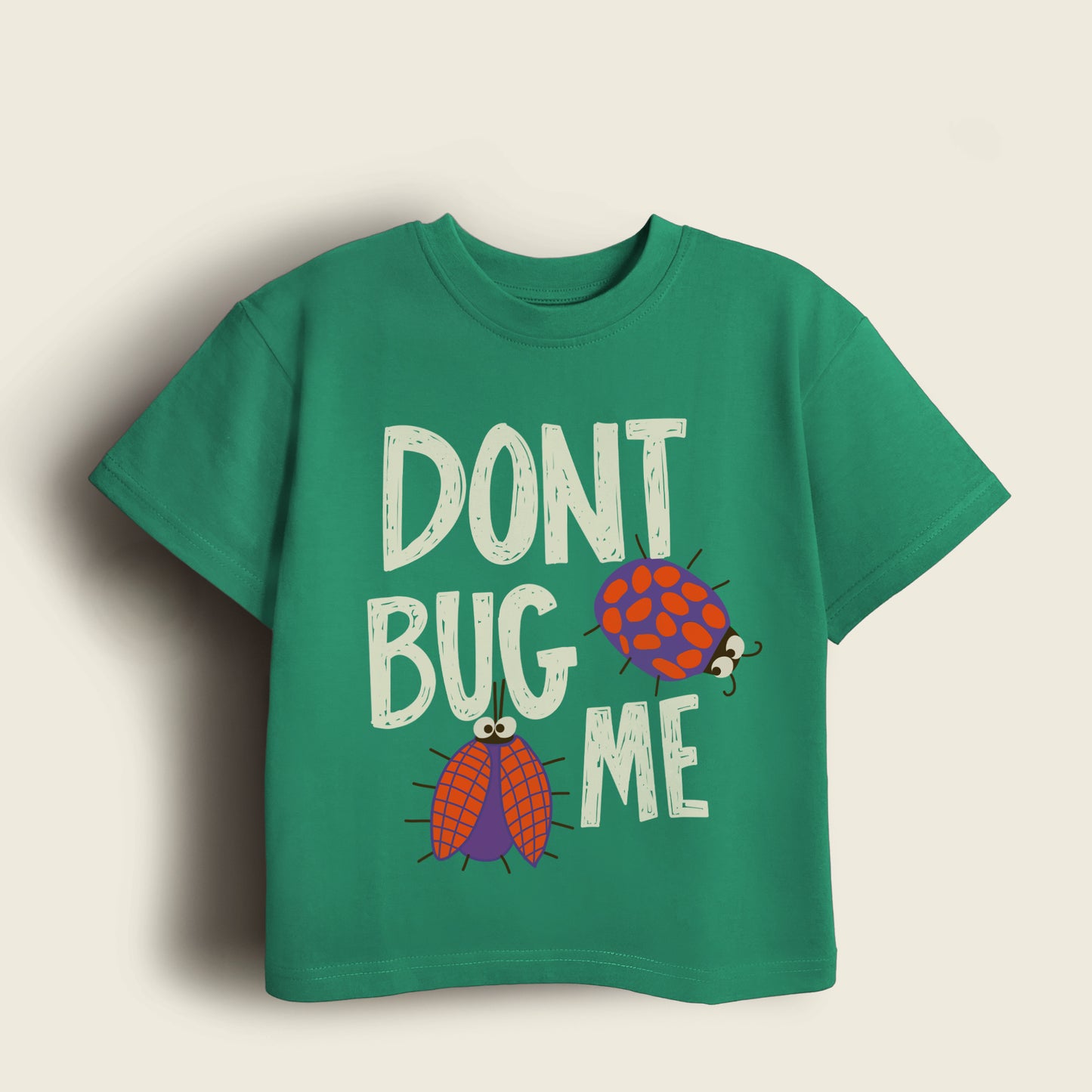Green t-shirt with 'Don't Bug Me' text and ladybug graphics on a beige background