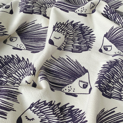 A close up of a Mapayah cotton bath towel featuring a porcupine print, neatly folded to show the design, fabric quality, and softness.

